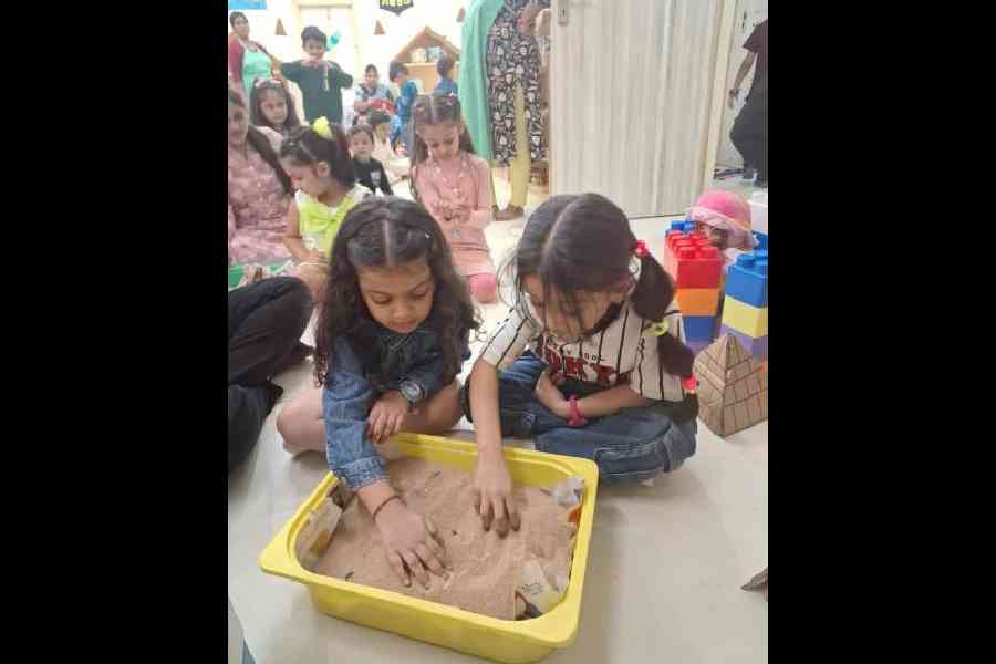 Girls search for gifts in sand, in the Egypt room