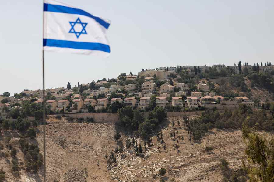 Israeli flag flutters, as part of the Israeli settlement of Maale Adumim is visible in the background, in the Israeli-occupied West Bank
