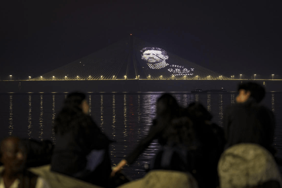 People look on as a portrait of Argentine football legend and 2022 FIFA World Cup-winning captain Lionel Messi is projected on the illuminated Bandra-Worli Sea Link, amid his ongoing ‘G.O.A.T. India Tour 2025’, in Mumbai, Maharashtra, Saturday, Dec. 13, 2025.