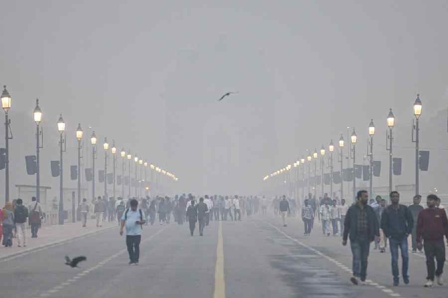 Smog engulfs Kartavya Path as people take a stroll amid low visibility, near the India Gate in New Delhi, Saturday, Dec. 13, 2025.
