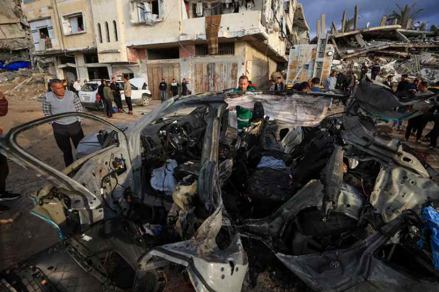 Palestinians inspect the site of an Israeli strike on a car in Gaza City, December 13, 2025.