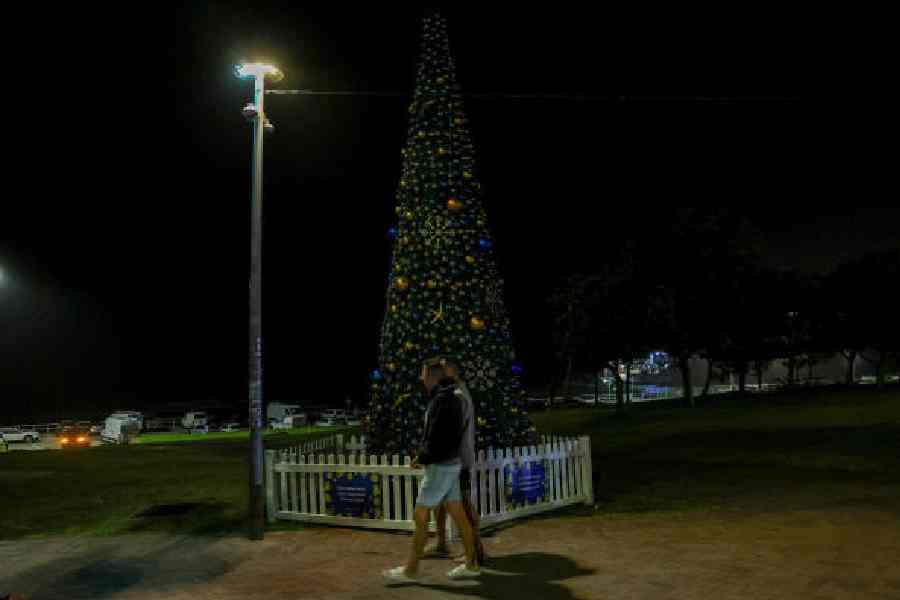 People walk past a Christmas tree at the scene of the shooting at Bondi Beach in Sydney on Sunday. 