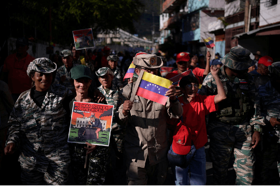 Members of the Bolivarian Militia wave Venezuelan flags and posters that read “No more war for oil. The world demands it.” during a protest against the U.S. seizure of a tanker transporting Venezuelan oil, in Caracas, Venezuela December 13, 2025.