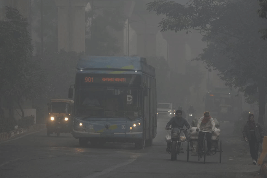 Vehicles move on a road amid low visibility due to a layer of smog, in New Delhi.