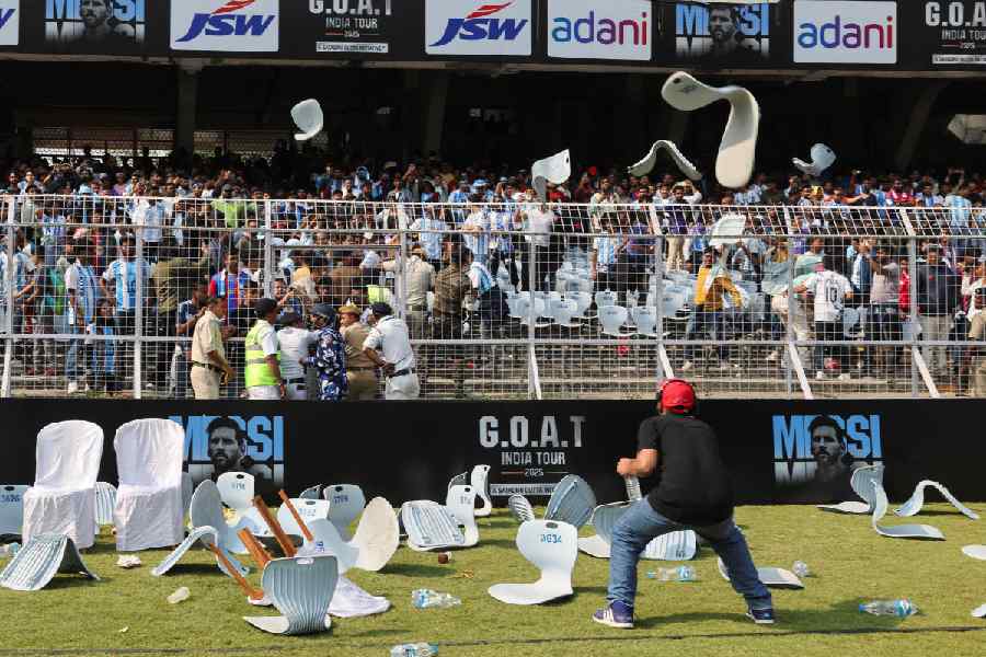 A man ducks to protect himself as fans throw chairs after Argentine soccer star Lionel Messi leaves the Vivekananda Yuva Bharati Krirangan stadium during his India tour, in Kolkata, India, December 13, 2025.