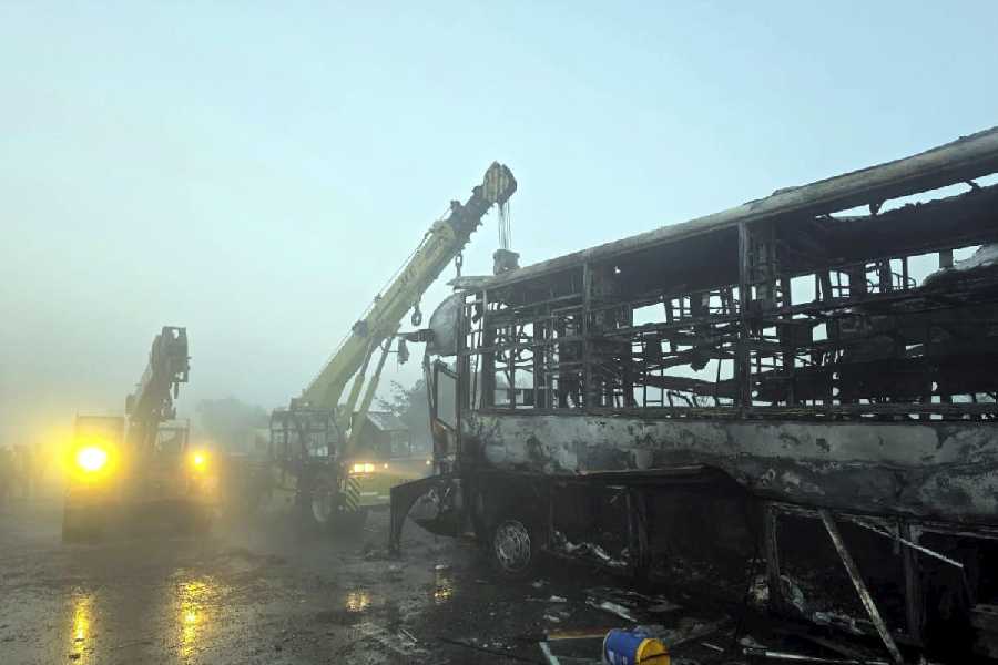Cranes clear the charred remains of buses on the Yamuna Expressway in Mathura on Tuesday.
