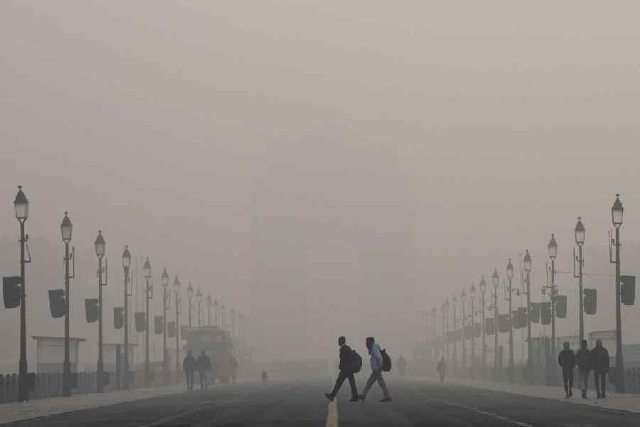 Visitors walk across the Kartavya Path near the India Gate on a smoggy winter morning, in New Delhi, Wednesday, Dec. 17, 2025.