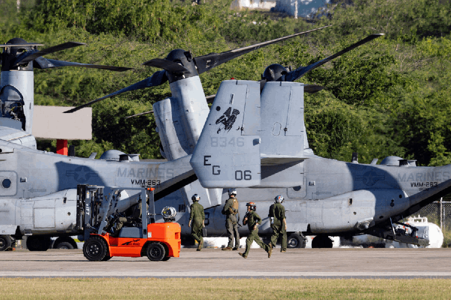 Personnel walk next to U.S. Marine Corps MV-22B Ospreys parked on the tarmac at Mercedita International Airport in Ponce amid ongoing military movements in Puerto Rico, December 18, 2025.