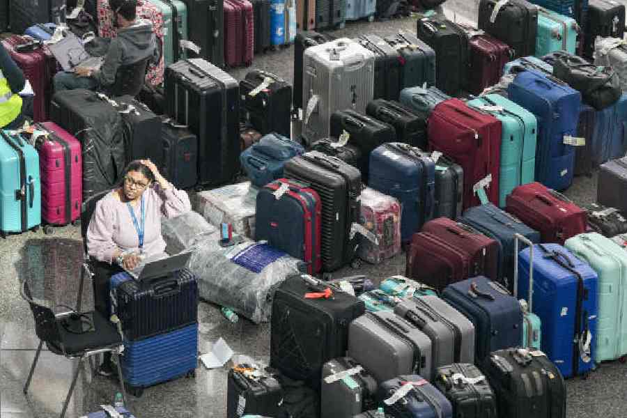 An IndiGo official works next to heaps of luggage piled up at the Indira Gandhi International Airport last week
