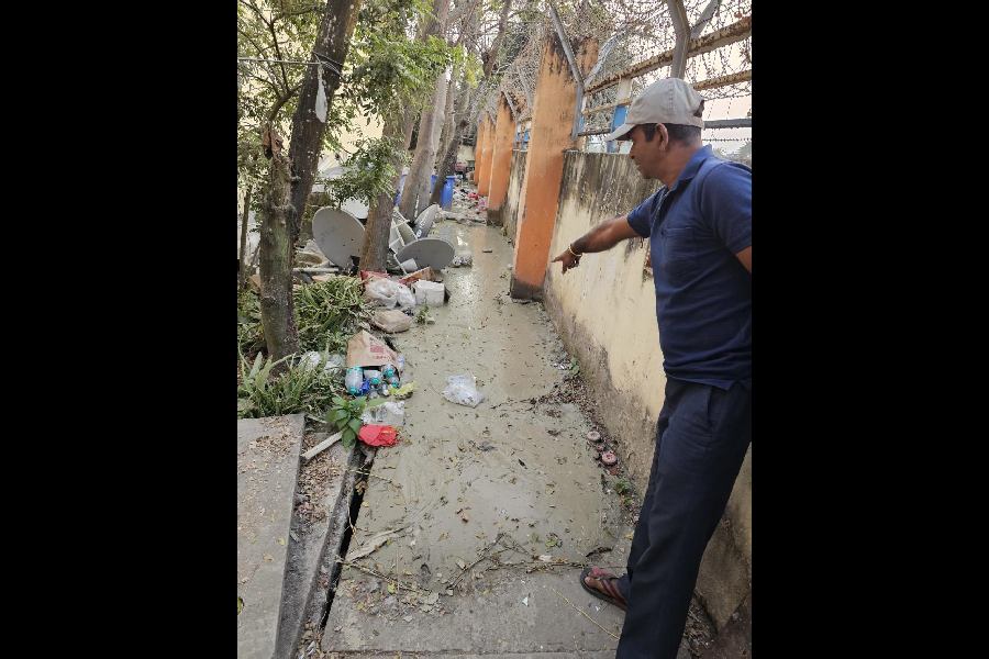 A staff member points to the slurry seeping into the compound of Greenwood Elements from the adjacent dumping field through the base of its boundary wall