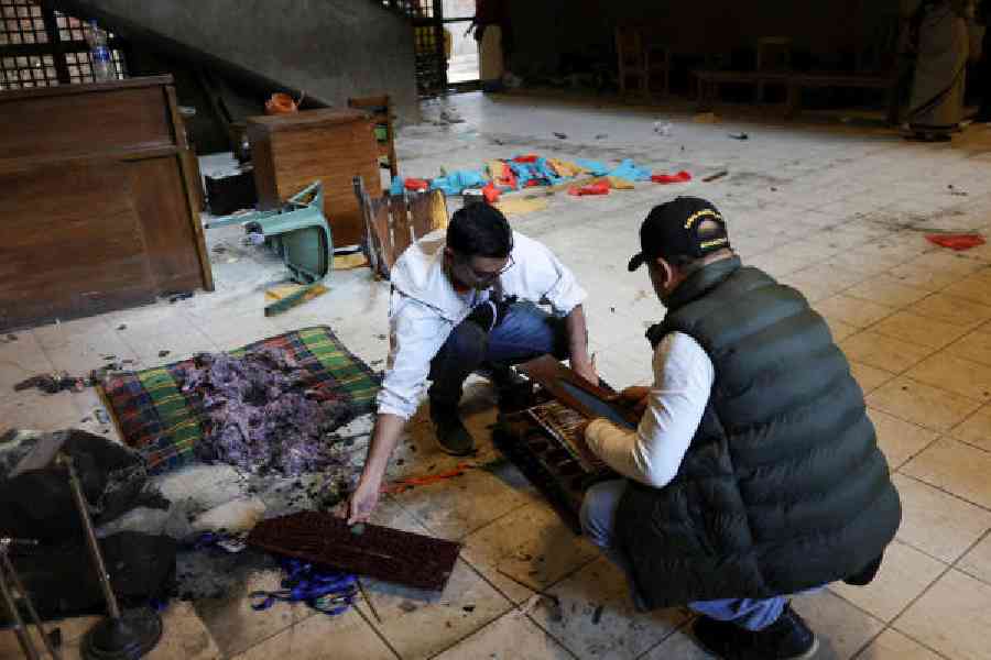 Two men on Friday sort a damaged harmonium at Chhayanaut, which was vandalised in Dhaka. (Reuters)
