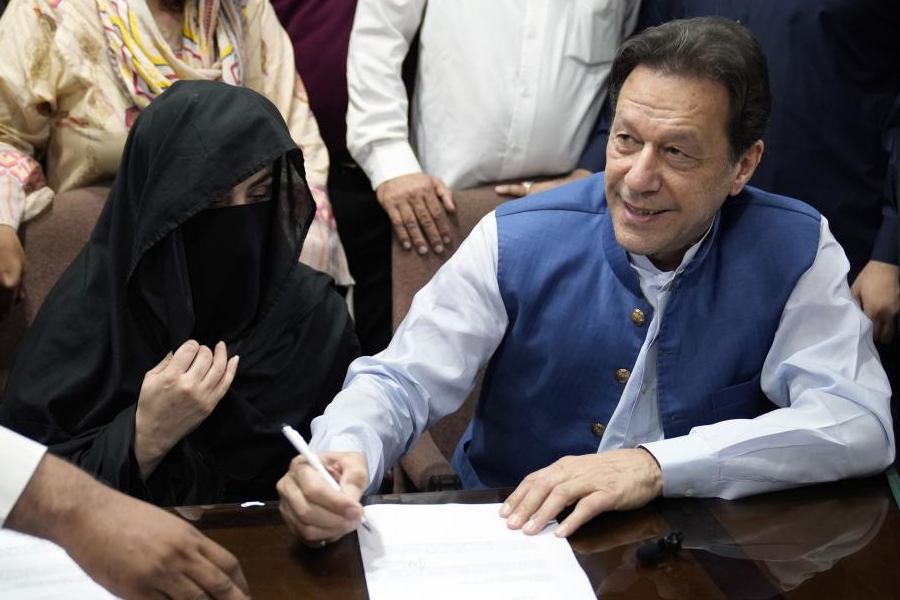 Pakistan's former Prime Minister Imran Khan, right, and Bushra Bibi, his wife, sign documents as he submits surety bond over his bails in different cases, at an office of Lahore High Court in Lahore, Pakistan, on July 17, 2023.