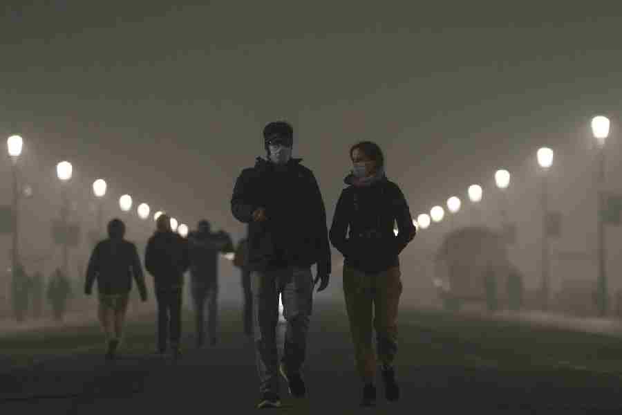 Pedestrians wear masks as a layer of smog engulfs the city amid deterioration in the capital's air quality, in New Delhi, Thursday, Dec. 18, 2025.