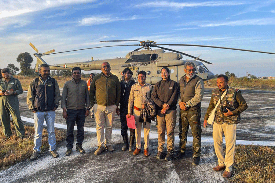 Forest and wildlife officials pose in front of an Indian Air Force Mi-17 helicopter at Sukatra airstrip during the country's first inter-state tiger translocation operation, in Seoni, Madhya Pradesh, Sunday, Dec. 21, 2025.