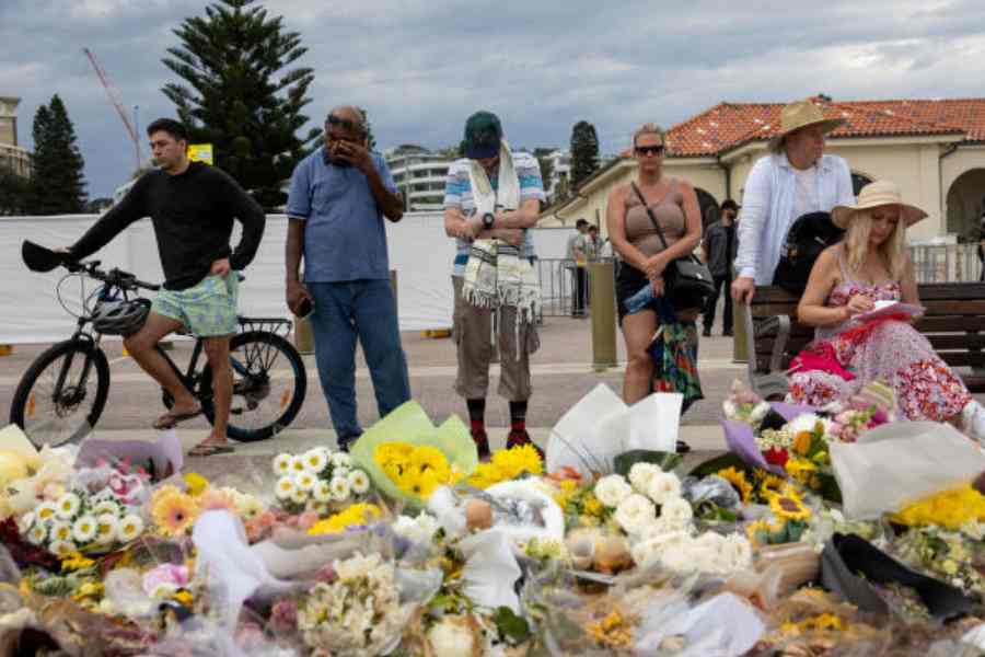People mourn near floral tributes for victims and survivors of the Bondi Beach shooting in Sydney on Sunday. 