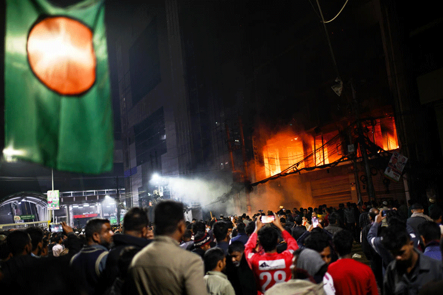 A crowd gathers near the premises of the Prothom Alo daily newspaper which was set on fire by angry protesters after news reached the country from Singapore of the death of a prominent activist Sharif Osman Hadi, in Dhaka, Bangladesh, Friday, Dec. 19, 2025.