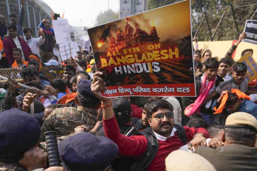 Police personnel attempt to stop members of Vishva Hindu Parishad (VHP) and Bajrang Dal protesting against the alleged attacks on Hindus in Bangladesh, near Bangladesh High Commission, in New Delhi,