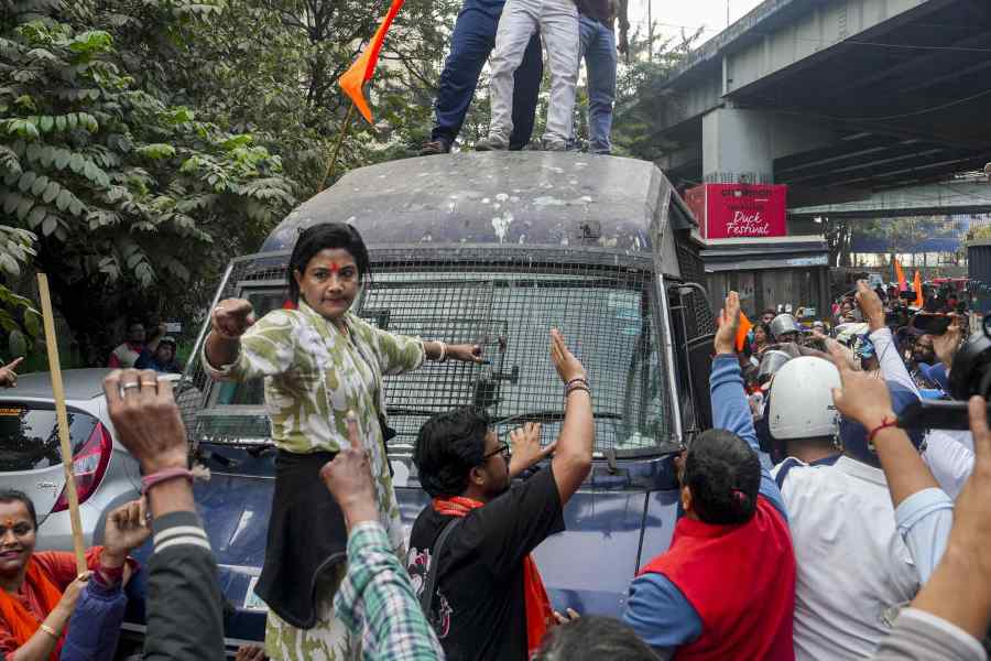 Members of West Bengal Hindu Jagran stand on top of a police van as police personnel detain other agitators during a protest against the killing of a Hindu youth in Bangladesh, near the Bangladesh Deputy High Commission, in Kolkata