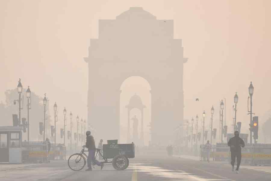 The India Gate shrouded in a layer of smog as people make their way during a cold winter morning, at Kartavya Path, in New Delhi, Wednesday, Dec. 24, 2025.