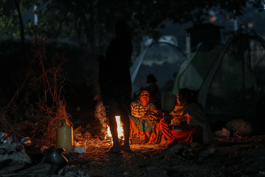 People sit around a small fire as temperatures drop during winter, in Kolkata.