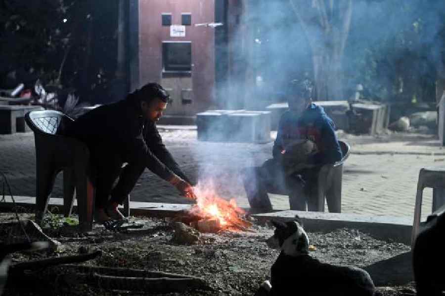 Two men light a fire to keep themselves warm at BBD Bagh area