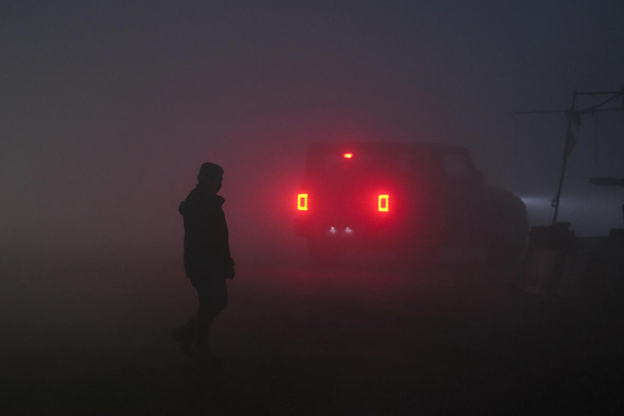 A person crosses a road as a dense layer of fog blankets the area, affecting visibility on a winter morning, in New Delhi, Monday, Dec. 29, 2025.