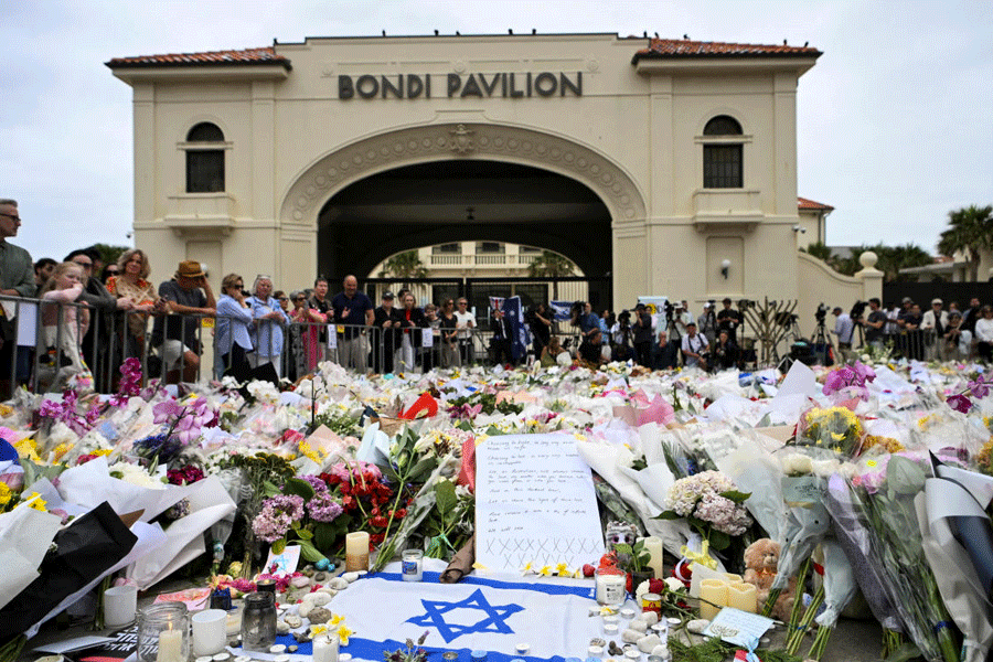 People stand near flowers laid as a tribute at Bondi Beach to honour the victims of a mass shooting that targeted a Hanukkah celebration at Bondi Beach on Sunday, in Sydney, Australia, December 16, 2025.