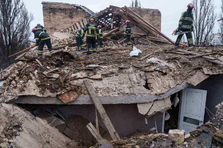 Rescue workers clear the rubble at the roof of apartment building damaged after a Russian strike on Kyiv, Ukraine, on Saturday, Dec. 27, 2025.