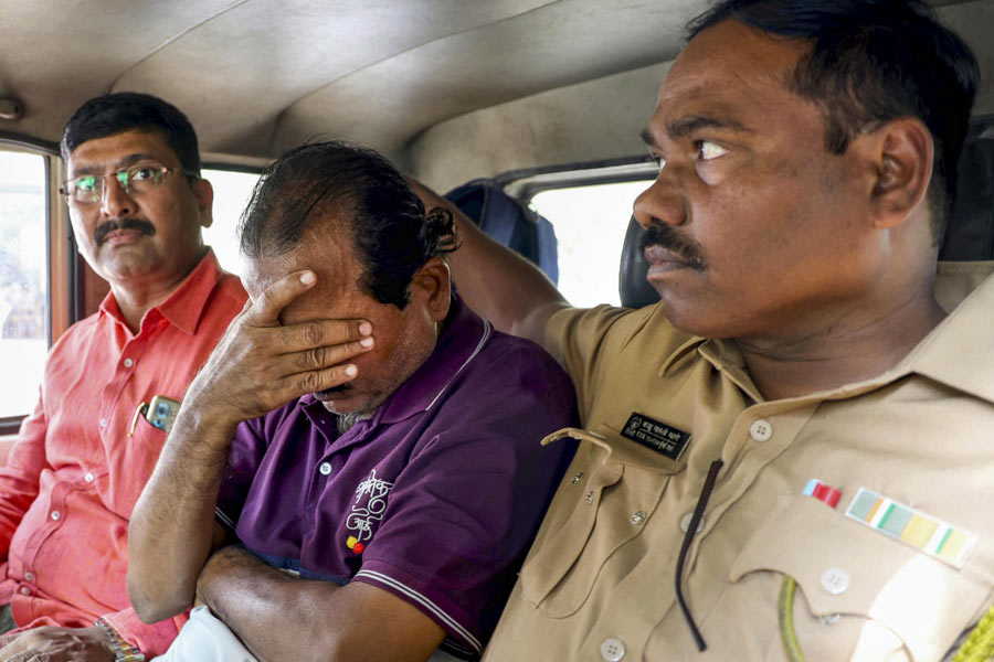 BEST bus driver Santosh Sawant covers his face, flanked by policemen, inside a police vehicle as he is produced before the Vikhroli court and remanded to police custody till January 3, in Mumbai, Tuesday, Dec. 30, 2025. Sawant was driving the BEST bus that ran over pedestrians in Bhandup on Monday night, killing four people and injuring eight others.