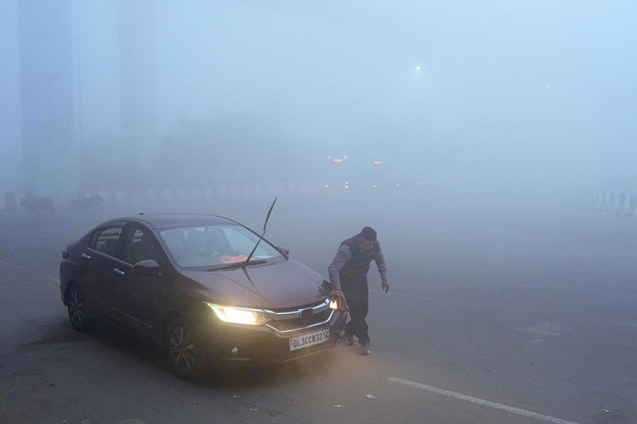 A man cleans his car amid dense fog on a cold winter morning, in New Delhi.