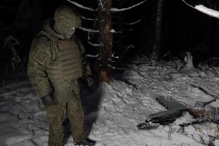 A Russian service member stands next to the remains of a drone, which, according to the Russian Defence Ministry, was downed during the repelling of an alleged Ukrainian attack on the Russian presidential residence in the Novgorod Region, in an unknown location in Russia, in this still image from a video released December 31, 2025.