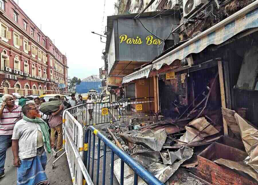 Passers-by look at a gutted shop near the Kolkata Municipal Corporation headquarters in New Market area on Saturday. No injuries were reported