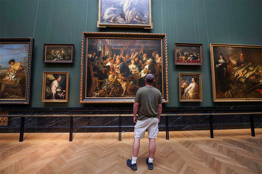 An art lover enjoying the large paintings on the wall inside the Kunsthistorisches Museum (Art History Museum)