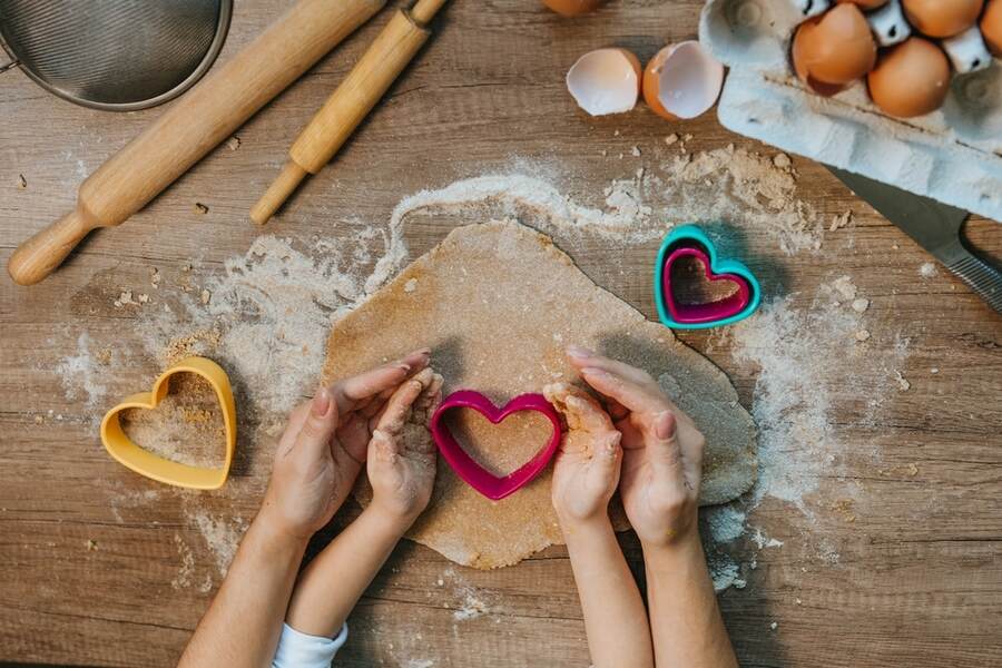 Kid and parent making heart shape cookies