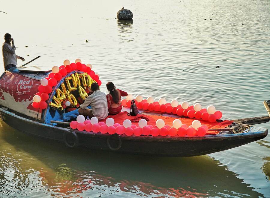 At Prinsep Ghat, a couple take a boat ride decorated with red and white balloons for V-Day  