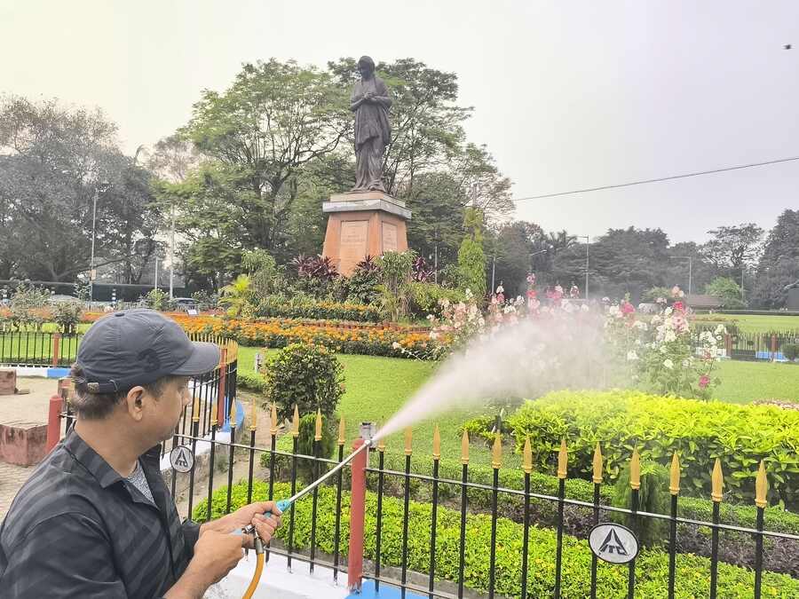 An employee of West Bengal Pollution Control Board sprays spray water and chemicals on a green patch at the Maidan on Tuesday to combat dust
