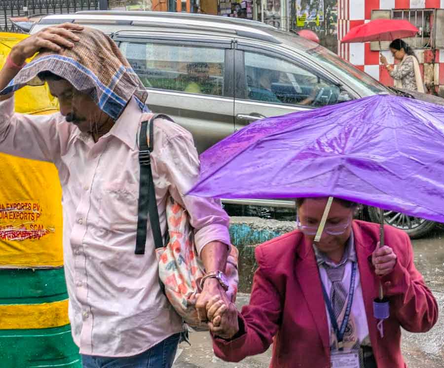 A student returns home with her guardian during rain in north Kolkata 
