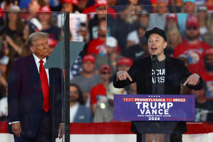 Tesla CEO and X owner Elon Musk speaks as Republican presidential nominee and former U.S. president Donald Trump looks on during a rally at the site of the July assassination attempt against Trump, in Butler, Pennsylvania, U.S., October 5, 2024.