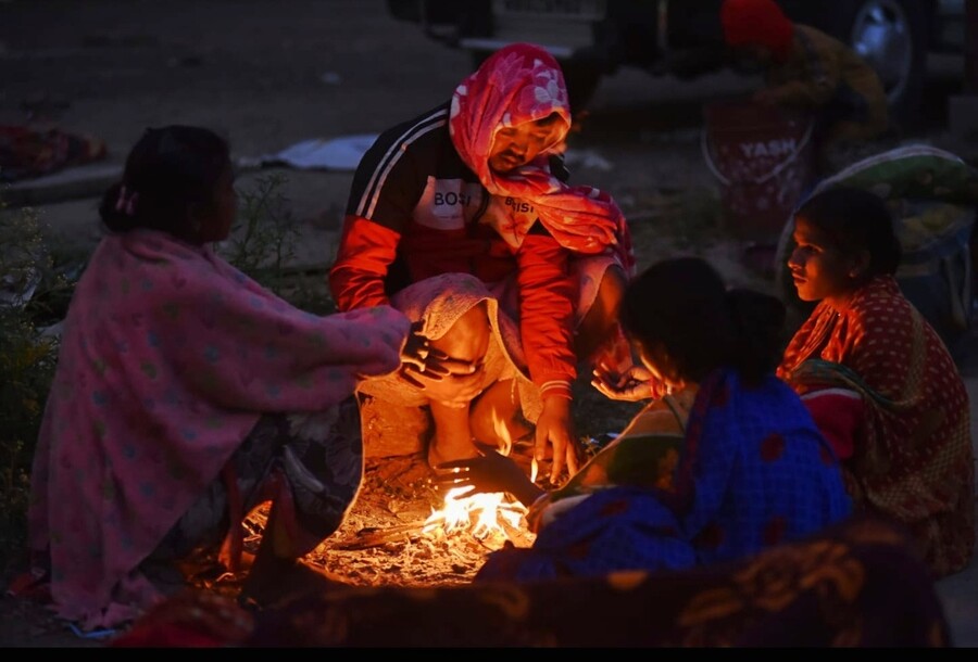 As the night gets chilly, people warm up near the fire. The minimum temperature on Friday was 13.2˚C