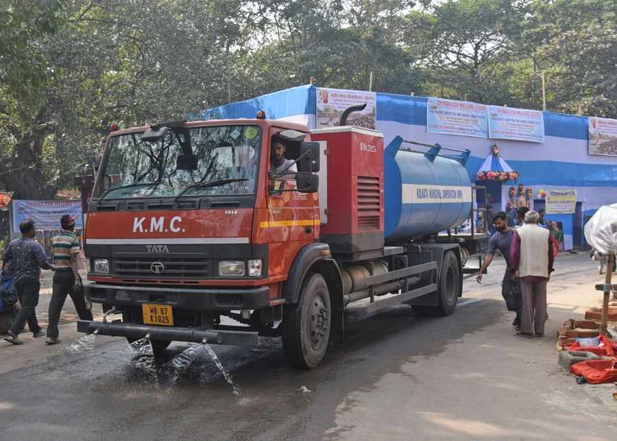 The Kolkata Municipal Corporation water department employees sprinkle water at the Gangasagar Mela 2025 transit camp at Babughat to tackle air pollution