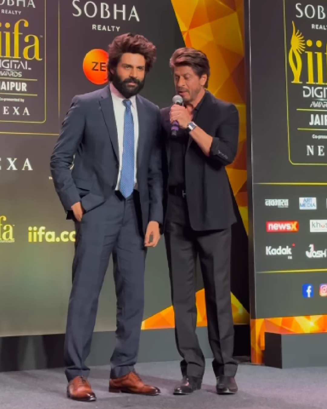 The Bhool Bhulaiyaa 3 actor shared stage with Bollywood superstar Shah Rukh Khan during the conference. Like Kartik, Shah Rukh sported a sleek black suit. But, it was his ear cuff that stole the show.