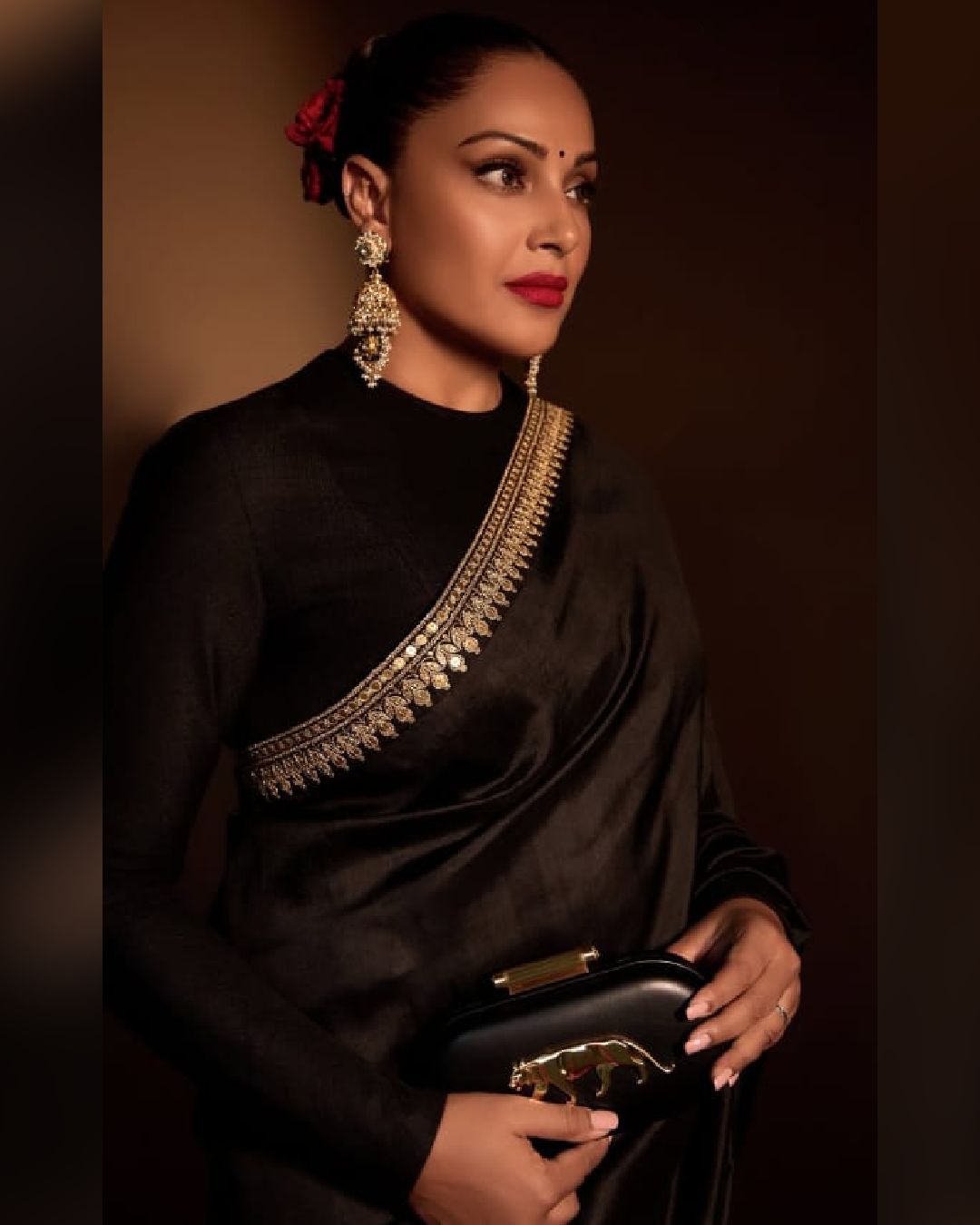 Bipasha Basu flaunted her impeccable style in a black sari with golden zari borders. The actress opted for a full-sleeved blouse and a statement clutch from Sabyasachi to accentuate her look. 