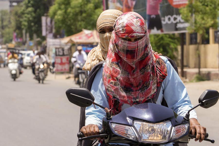 Students cover themselves in protection against the scorching heat on a hot summer day, in Beawar, Saturday, May 13, 2023.