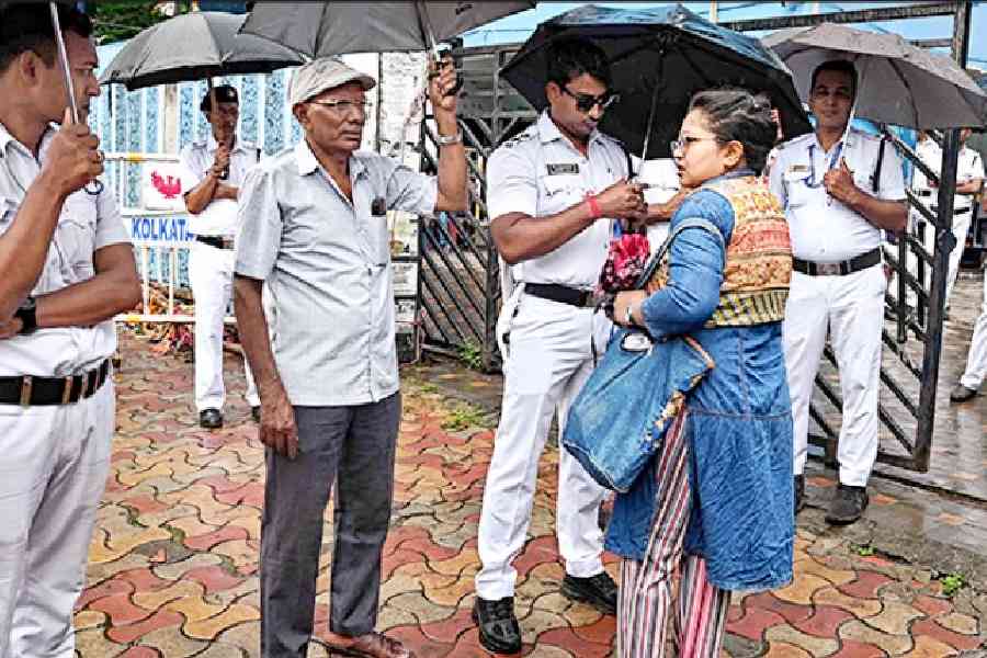 Cops and the security guard of the law college check an employee’s ID card on Monday