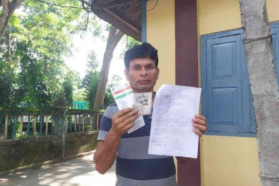 Uttam Brajabashi shows his identity proofs and the notice from the Assam Foreigner’s Tribunal in Dinhata on Sunday. Picture by Main Uddin Chisti