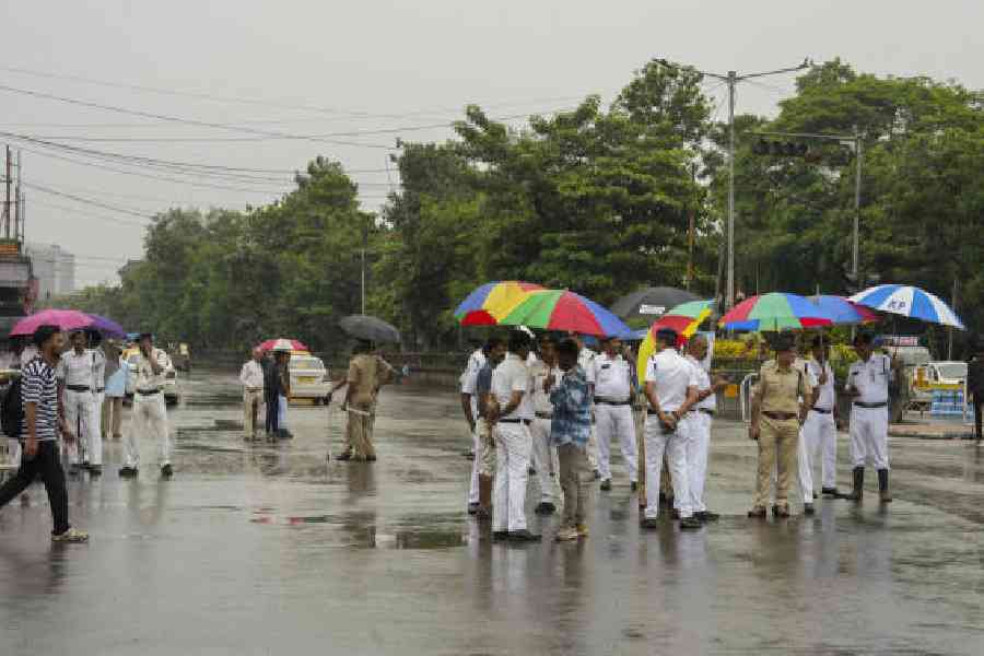 Police personnel keep vigil during rainfall amid a 24-hour nationwide general strike called by trade unions to protest against the central government's alleged anti-labour policies, at Esplannade area