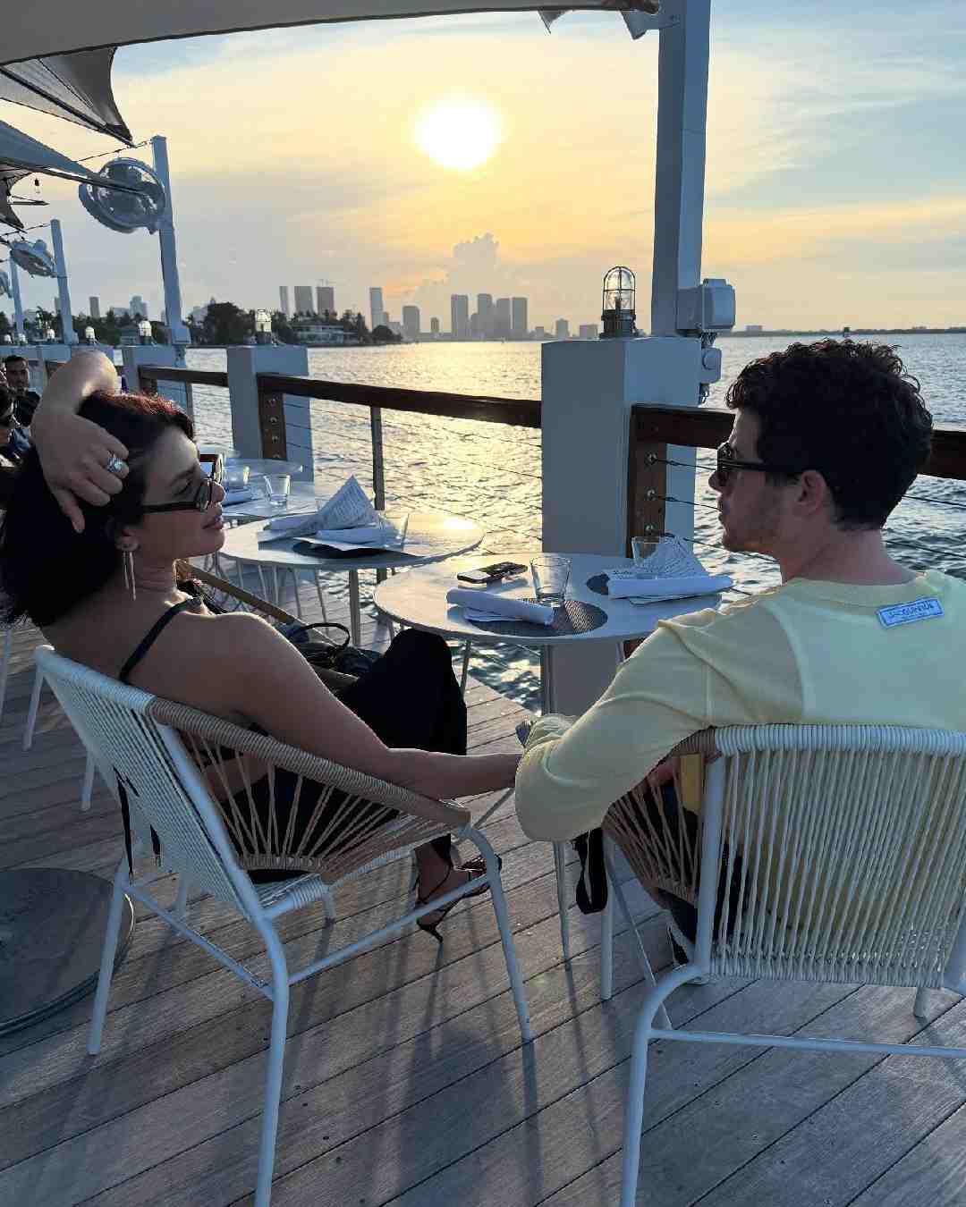 Priyanka and Nick relaxed on a restaurant’s deck, sitting on chairs and holding hands as they took in the ocean view.  