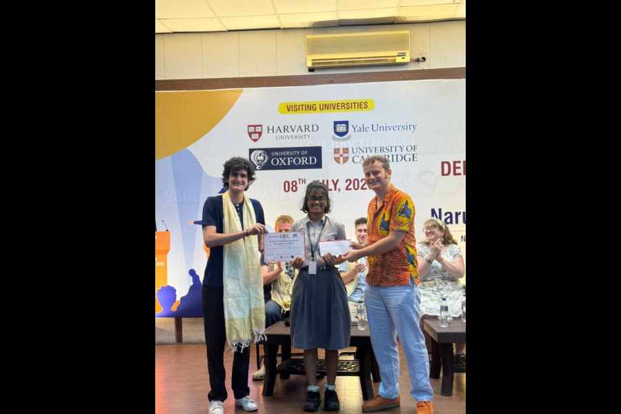 Arshia Dutta of Garden High School gets her award from Zachary Fleesler of Oxford University (extreme left) and debate coach Jordan Anderson from the UK.