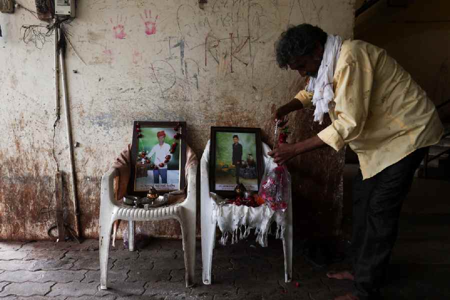 A family member of Akash Patni, who died after burning debris from the crashed plane fell on him, garlands his photo in Ahmedabad on July 13.