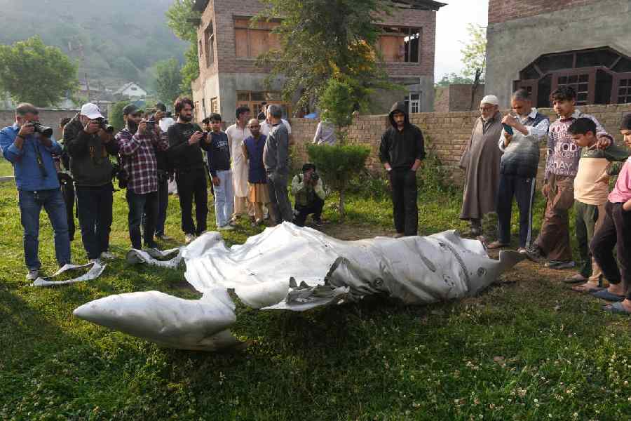 Local people gather near parts of an unknown jet that crashed after midnight, at Wuyan, Pampore, in Pulwama district, J&K